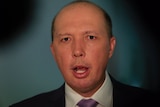 Peter Dutton captured with his mouth open mid sentence while wearing a navy suit and violet tie.