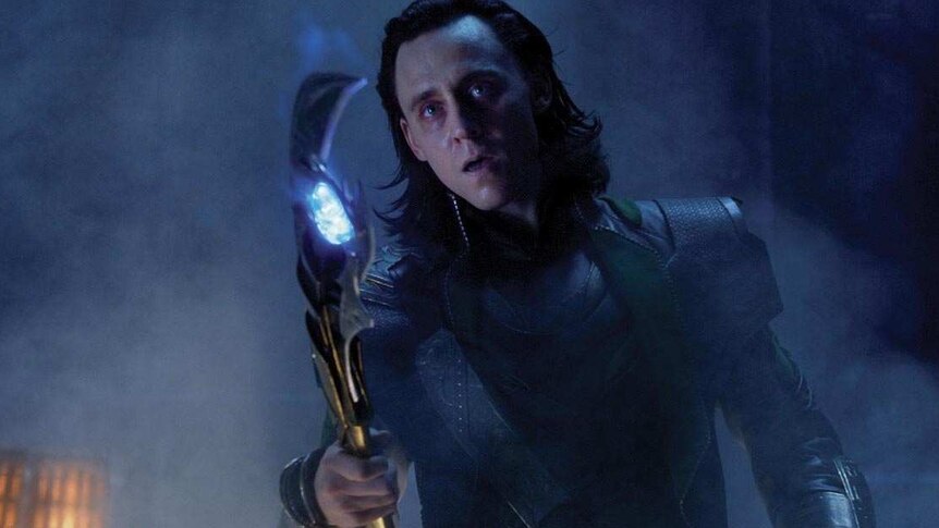 Loki holds a glowing sceptre.
