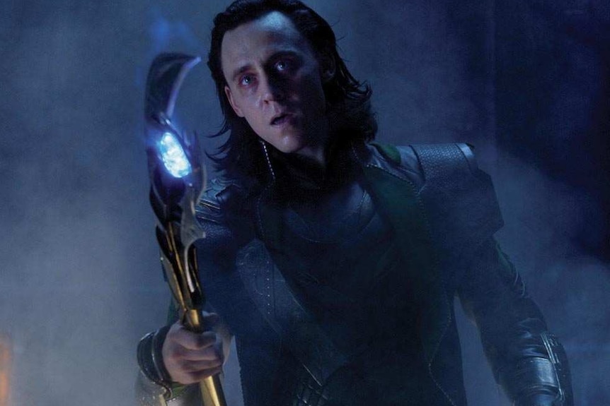 Loki holds a glowing sceptre.