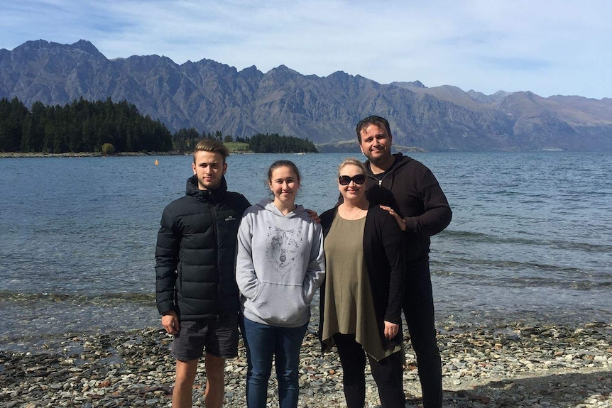 Sam Giancola, far right, his wife and two children at a lake with mountains in the background.