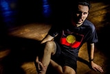 A shadowy  image of Robert McLellen wearing the Aboriginal flag