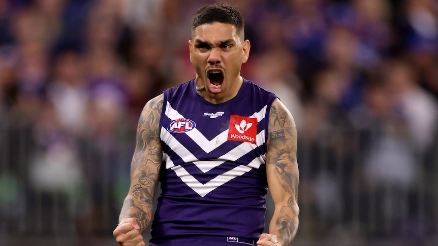 A Fremantle AFL player pumps his fists as he celebrates a goal.