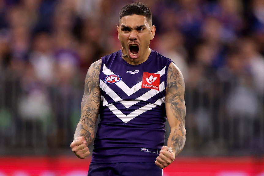 A Fremantle AFL player pumps his fists as he celebrates a goal.