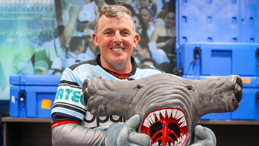 David Ninness holding the head of Sharks mascot MC Hammerhead.