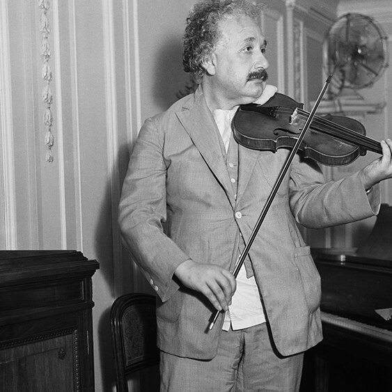 A black and white photo of Albert Einstein playing the violin.
