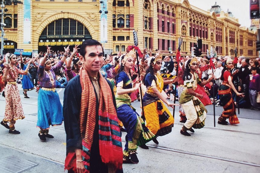 A group perform in Indian costume in the parade passing by outside Flinders street station, Melbourne.