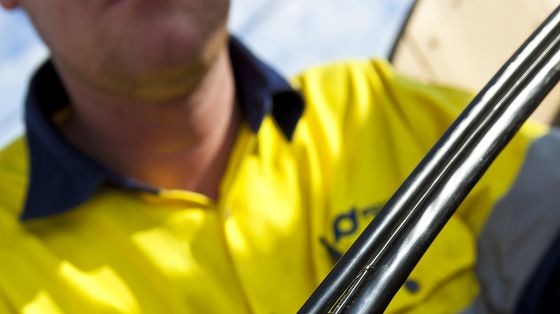 Hands hold an optic fibre wire during installation of Tasmania's National Broadband Network