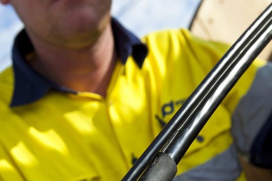 A worker holds a fibre optic cable during an NBN installation.