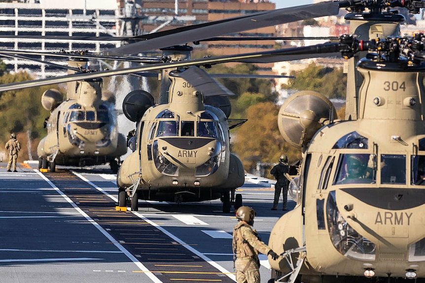 Three brown coloured Chinook helicopters on a tarmac 