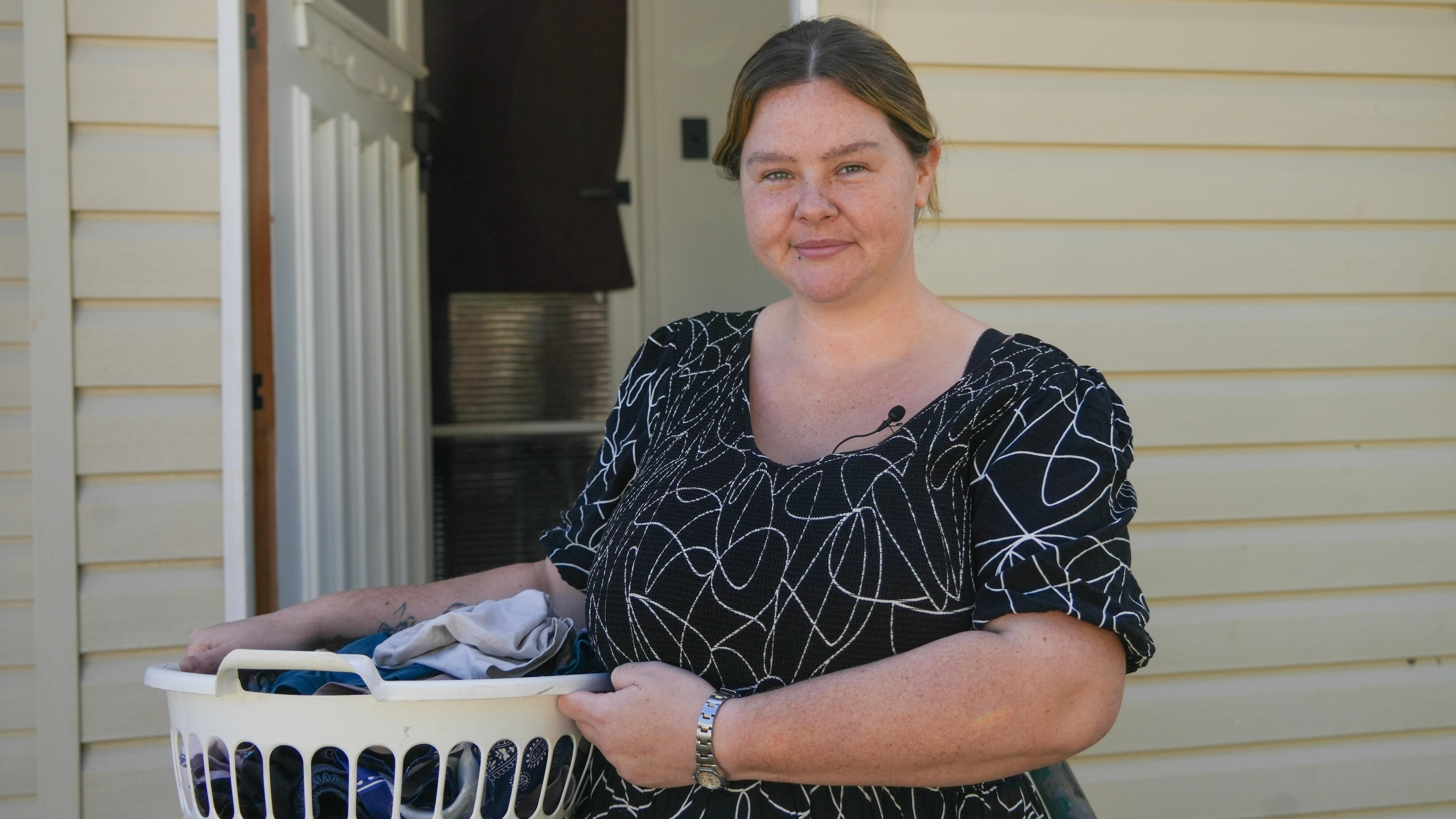 young woman in a black dress holding a basket of laundry.