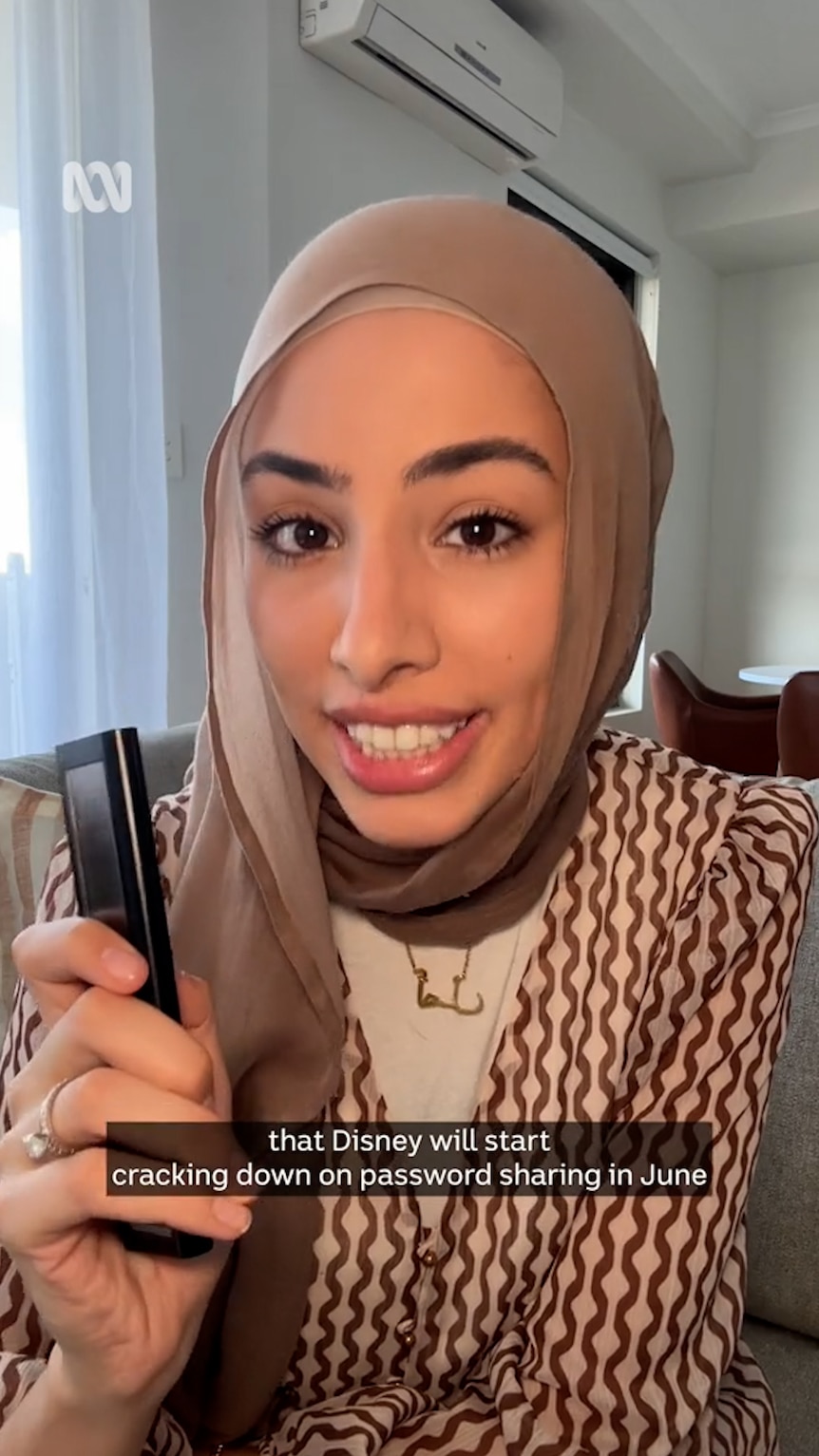 Woman in hijab smiles and holds a TV remote