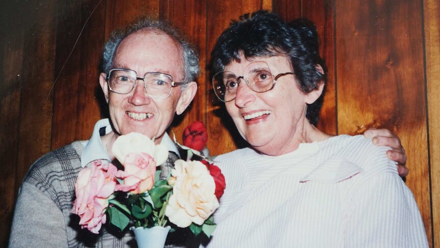 Stan McKay clutches a bouquet of flowers while smiling for a photo with his late wife Jean