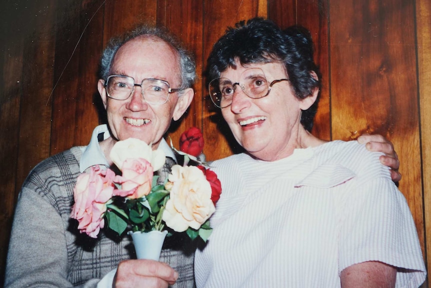 Stan McKay clutches a bouquet of flowers while smiling for a photo with his late wife Jean