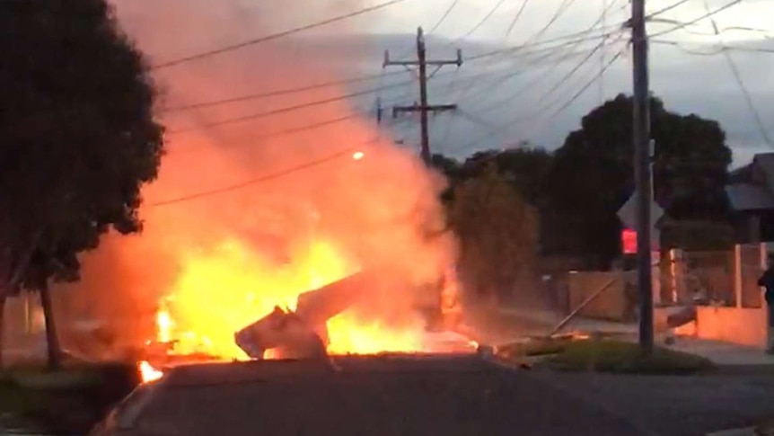 A screenshot taken from a supplied video showing a light plane on fire after crashing onto a street in Mordialloc.