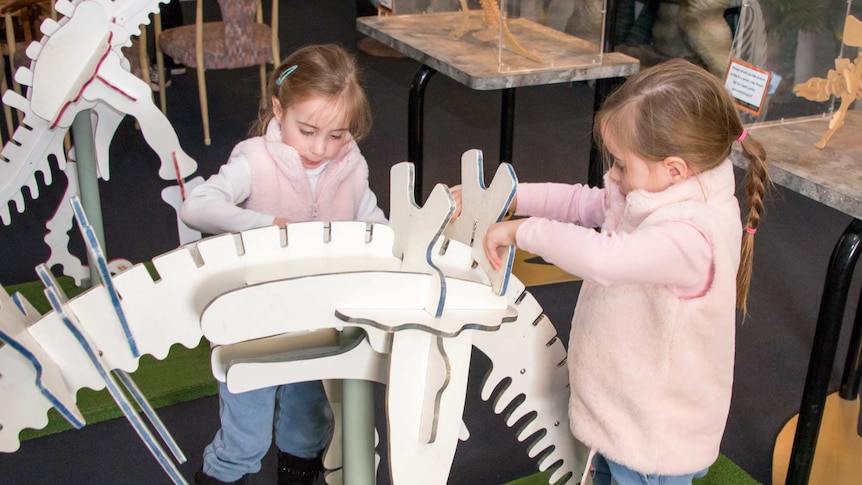 Twin girls putting together dinosaur puzzle