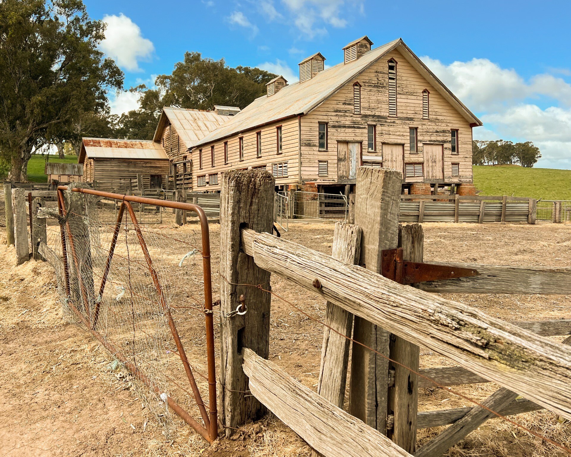 A wooden, historic timber woolshed with gate and wooden fence