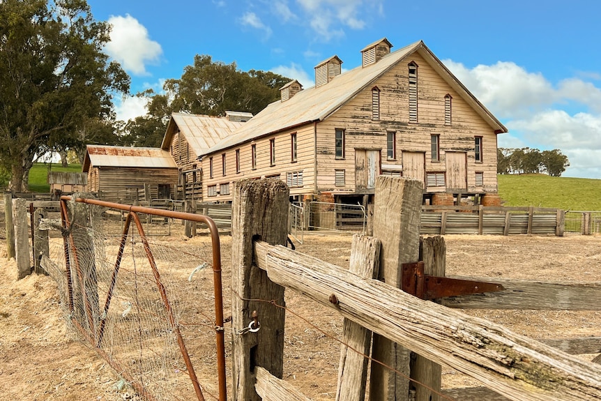 A wooden, historic timber woolshed with gate and wooden fence