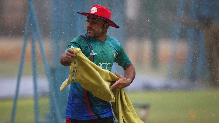 Afghanistan cricketer Rashid Khan runs for shelter during sudden rains at a training session.