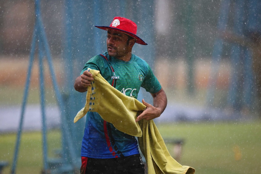 Afghanistan cricketer Rashid Khan runs for shelter during sudden rains at a training session.