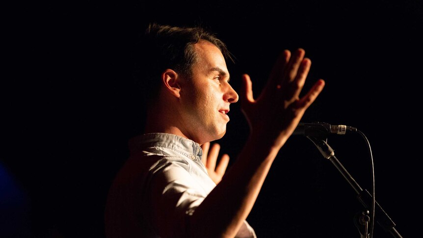 A man gestures and speaks into a microphone at the Moth storytelling grandslam in Sydney