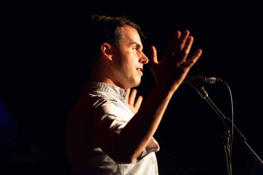 A man gestures and speaks into a microphone at the Moth storytelling grandslam in Sydney