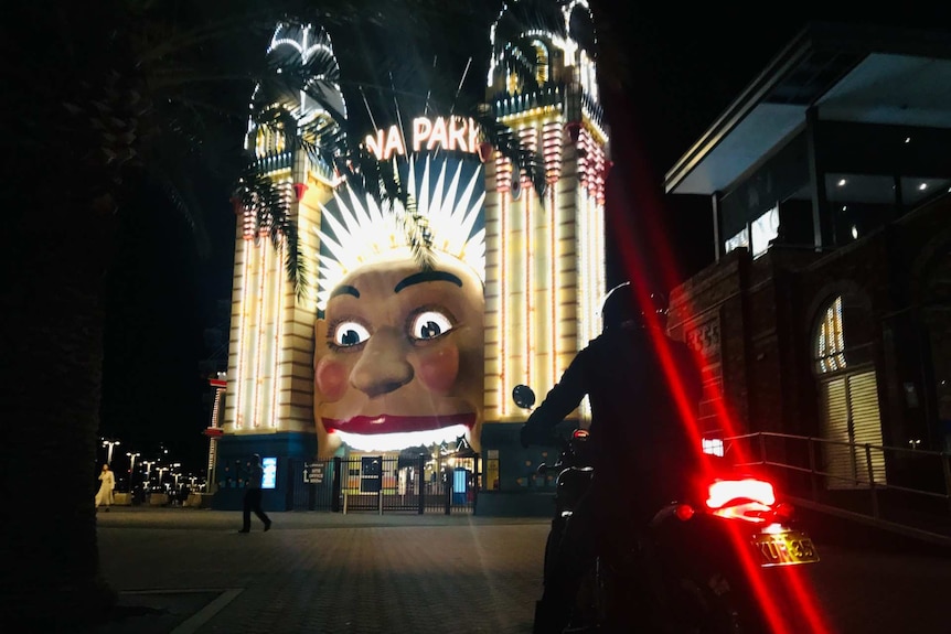 Night shot of face of Luna Park with motorbike in front.