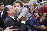 Francois Hollande kisses a child during a visit to Algieria.