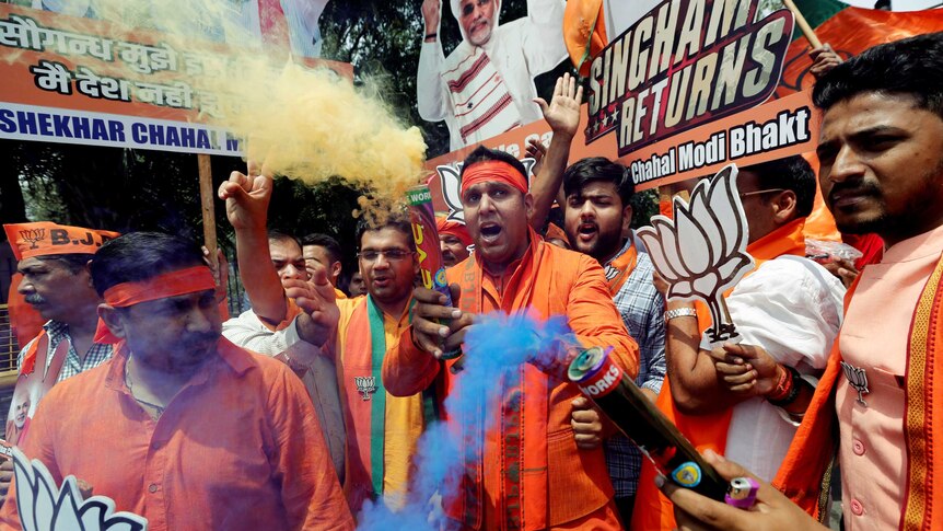 Men in orange outfits release coloured smoke bombs