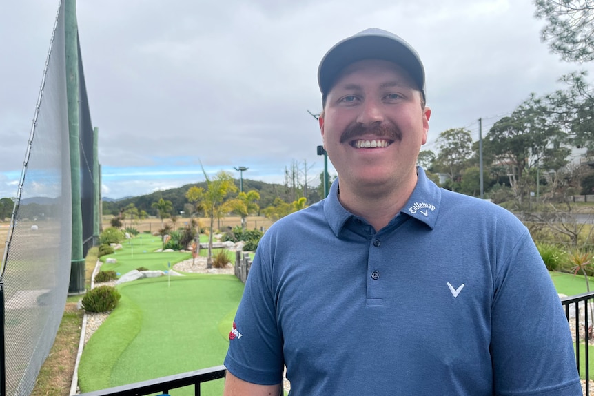 Plan de profil de Tom Major debout devant le minigolf de Coffs Coast. 