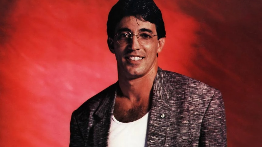 Ivan Lins standing in front of a red backdrop