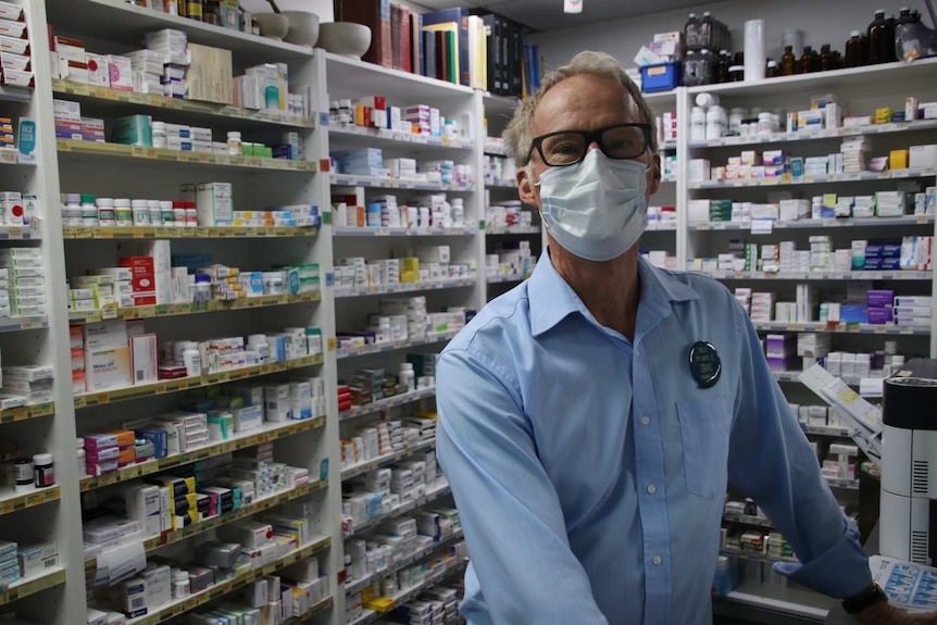 A pharmacist wearing a mask pictured in a pharmacy