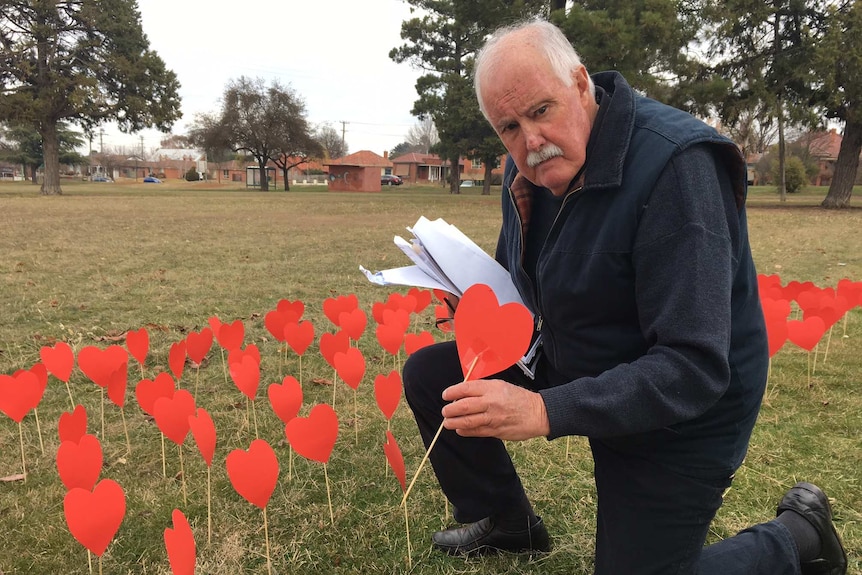 Former St Stanislaus student Terry Jones holds a cardboard heart as part of a vigil for sex abuse victims.
