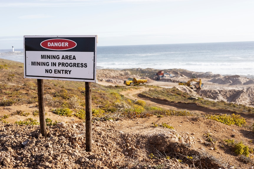 A beach with a sign that reads danger mining area mining in progress no entry