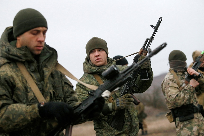 A row of young soldiers dressed in camo gear, holding rifles 