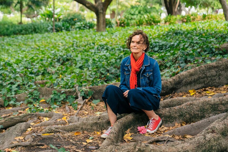 Andrea Hammond sits at the foot of a tree in a public garden in Perth.