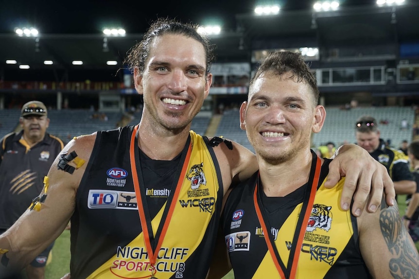 Nightcliff players Cameron Ilett and Phillip Wills smile at the camera with premiership medals around their neck.