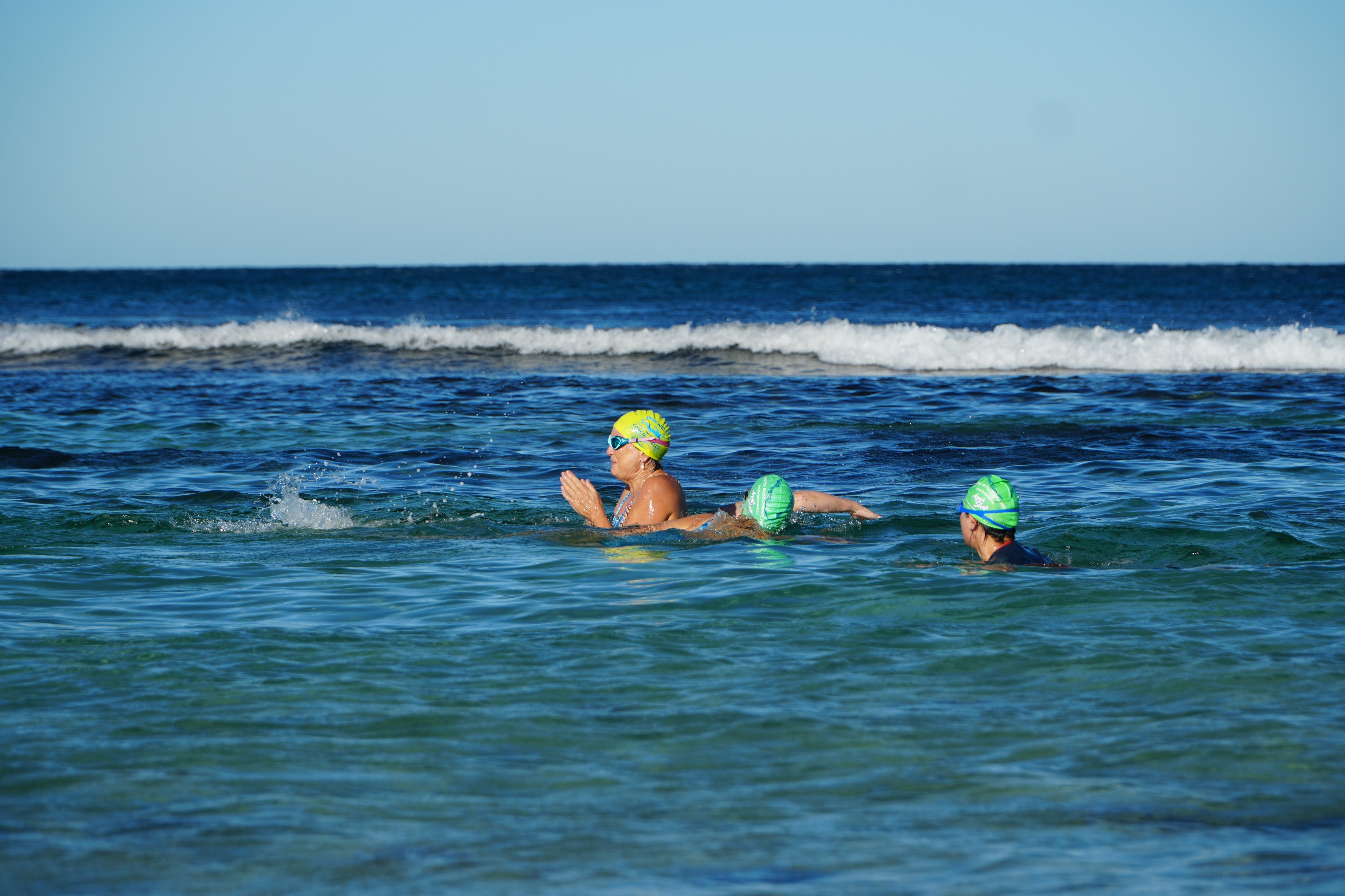 Mulheres usando toucas de banho e nadando.