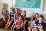 April Blair sitting on a couch with 7 children she is looking after.
