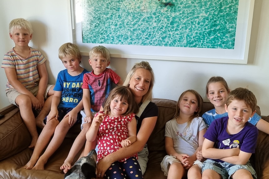 April Blair sitting on a couch with 7 children she is looking after.