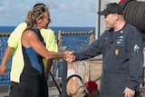 Jennifer Appel stands on a boat and shakes hands with USS Ashland Command Master Chief Gary Wise.
