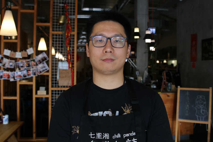 A man in a black t-shirt in a Chinese restraurant.