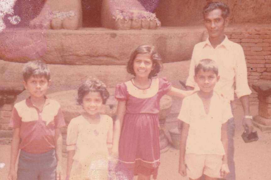 Four children and a man pose for a photo.