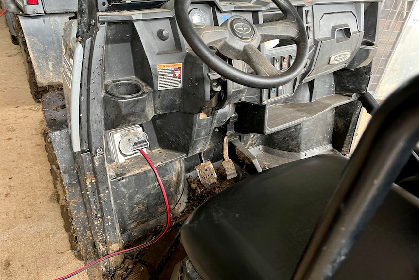 A power lead plugged into a socket on a muddy farm vehicle.