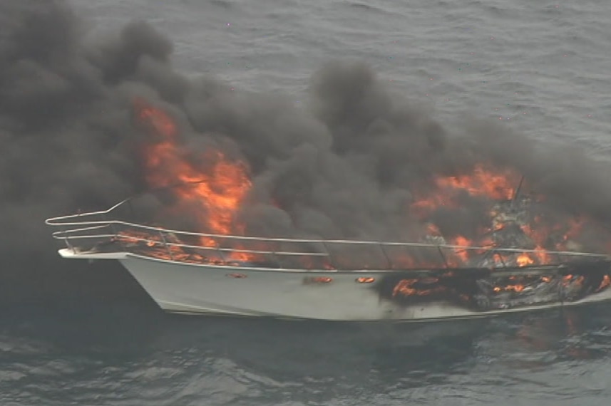 A close up of a burning boat in the ocean.