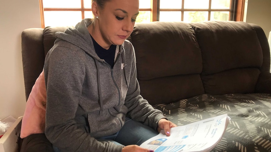 A woman on a sofa reading a bill