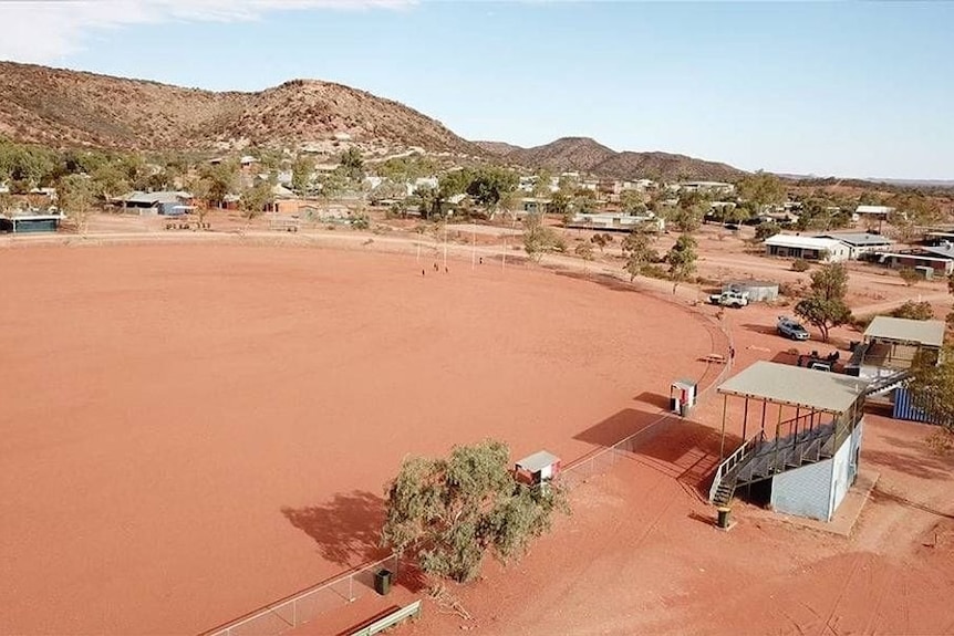 An aerial shot of a dusty oval with hills in the background.