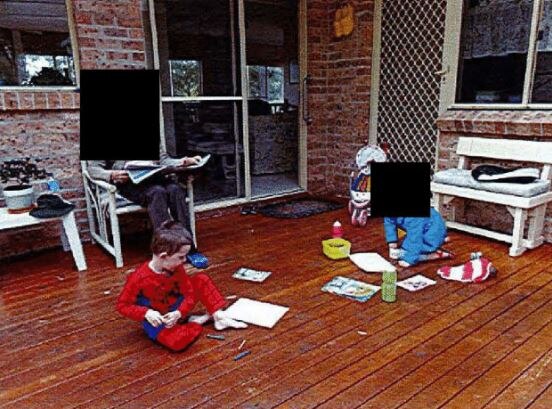 Two children play with crayons on a deck