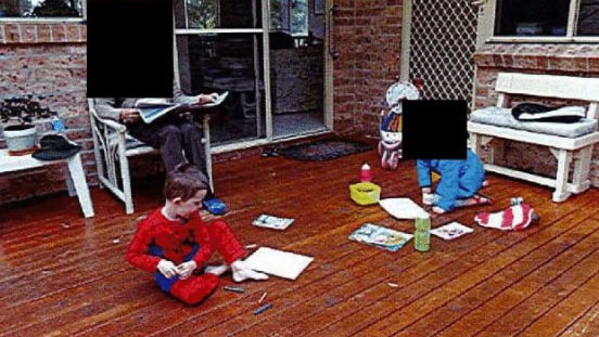 Two children play with crayons on a deck