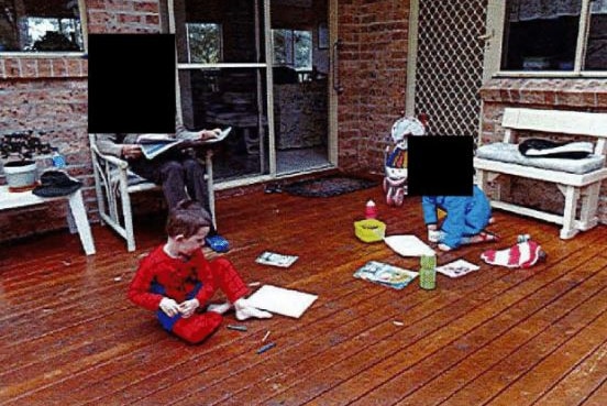 Two children play with crayons on a deck