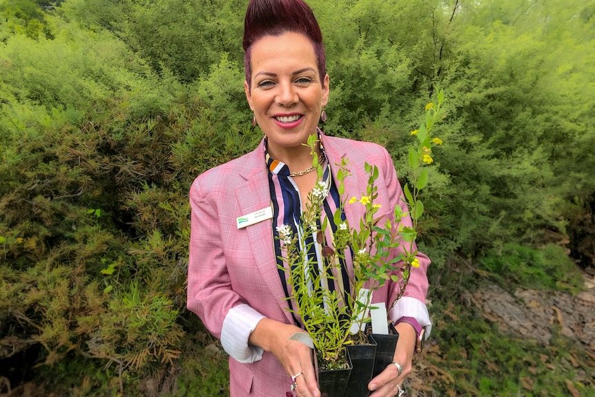 woman in pink jacket holds a pot plant